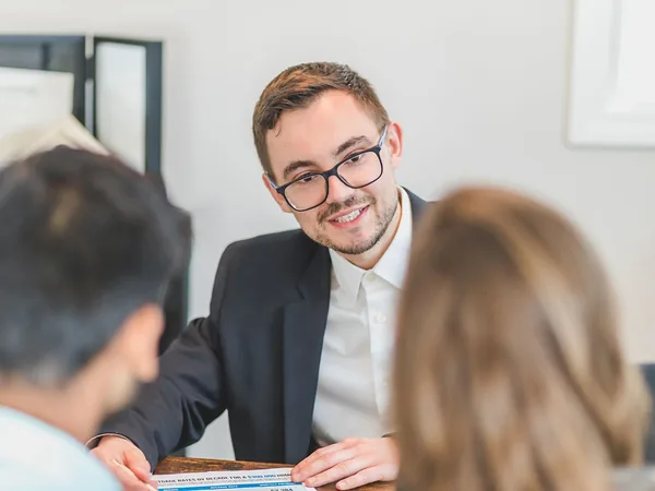 Un conseiller souriant échange avec un couple de clients
