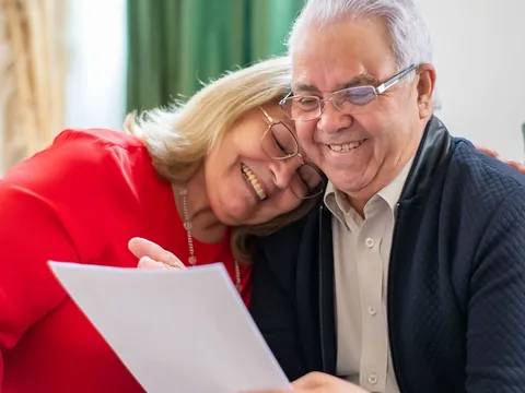 Un couple de retraités souriant découvre un document